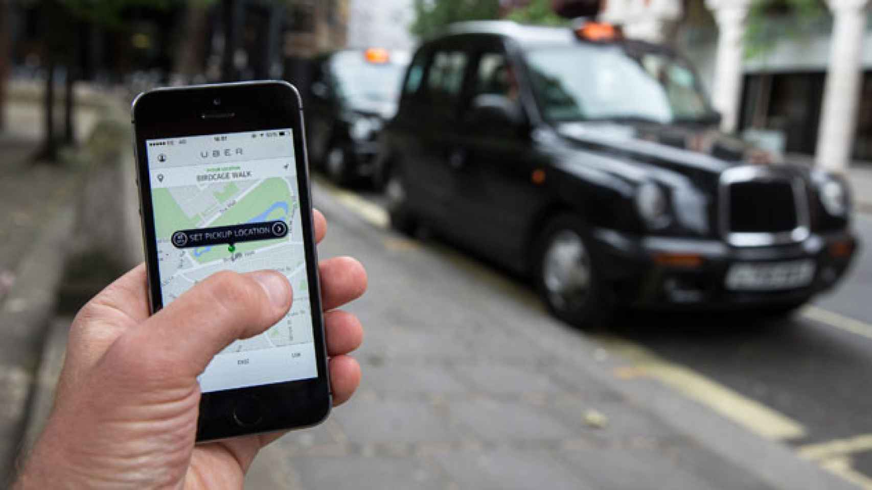 Imagen de un móvil con la 'app' de Uber con un taxi londinense de fondo / AP