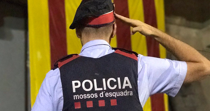 Imagen de un agente de los Mossos d'Esquadra saludando a una estelada en Vic (Barcelona) / EFE