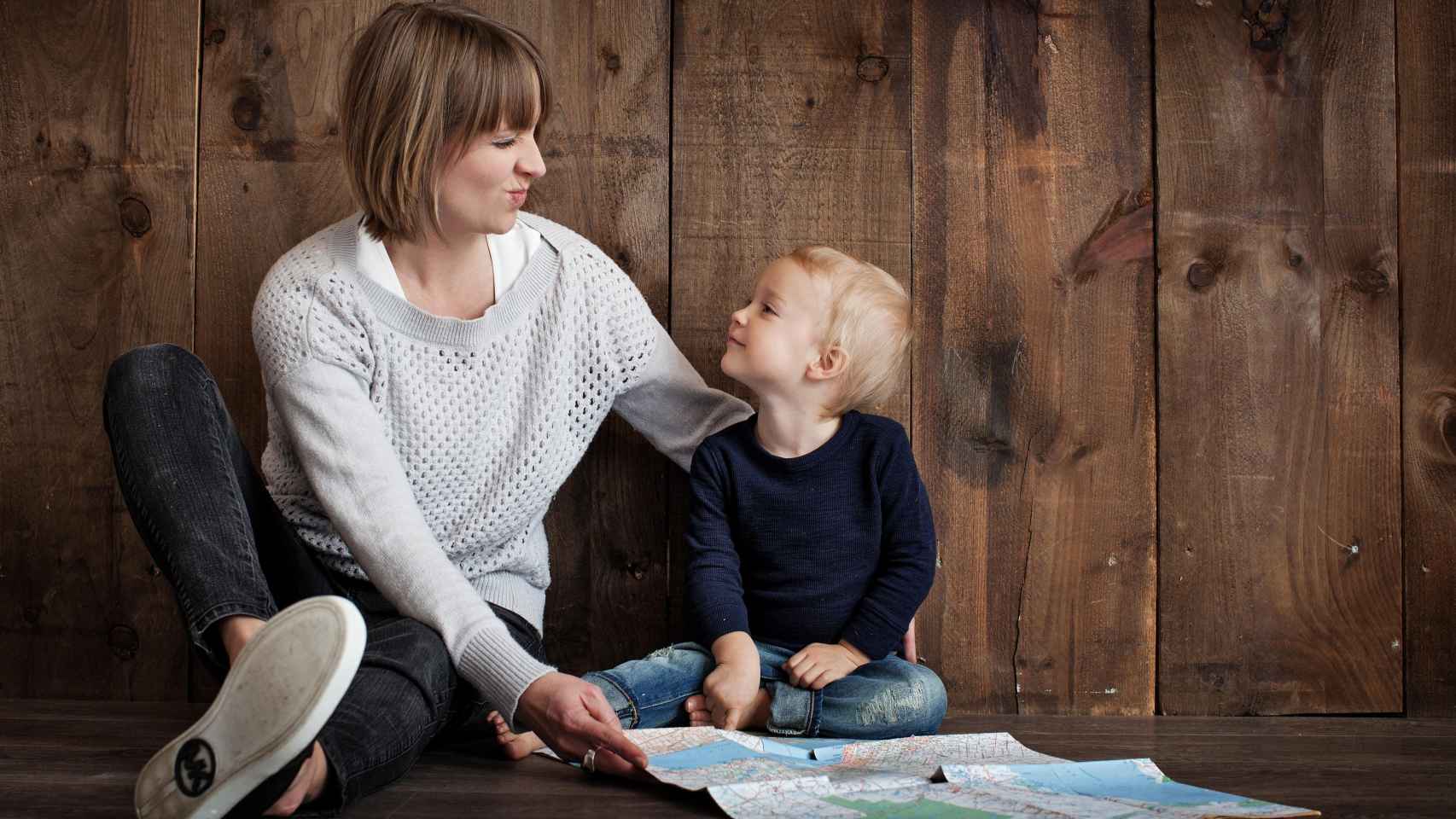 Imagen de una madre que juega con su hijo con un mapa / PEXELS