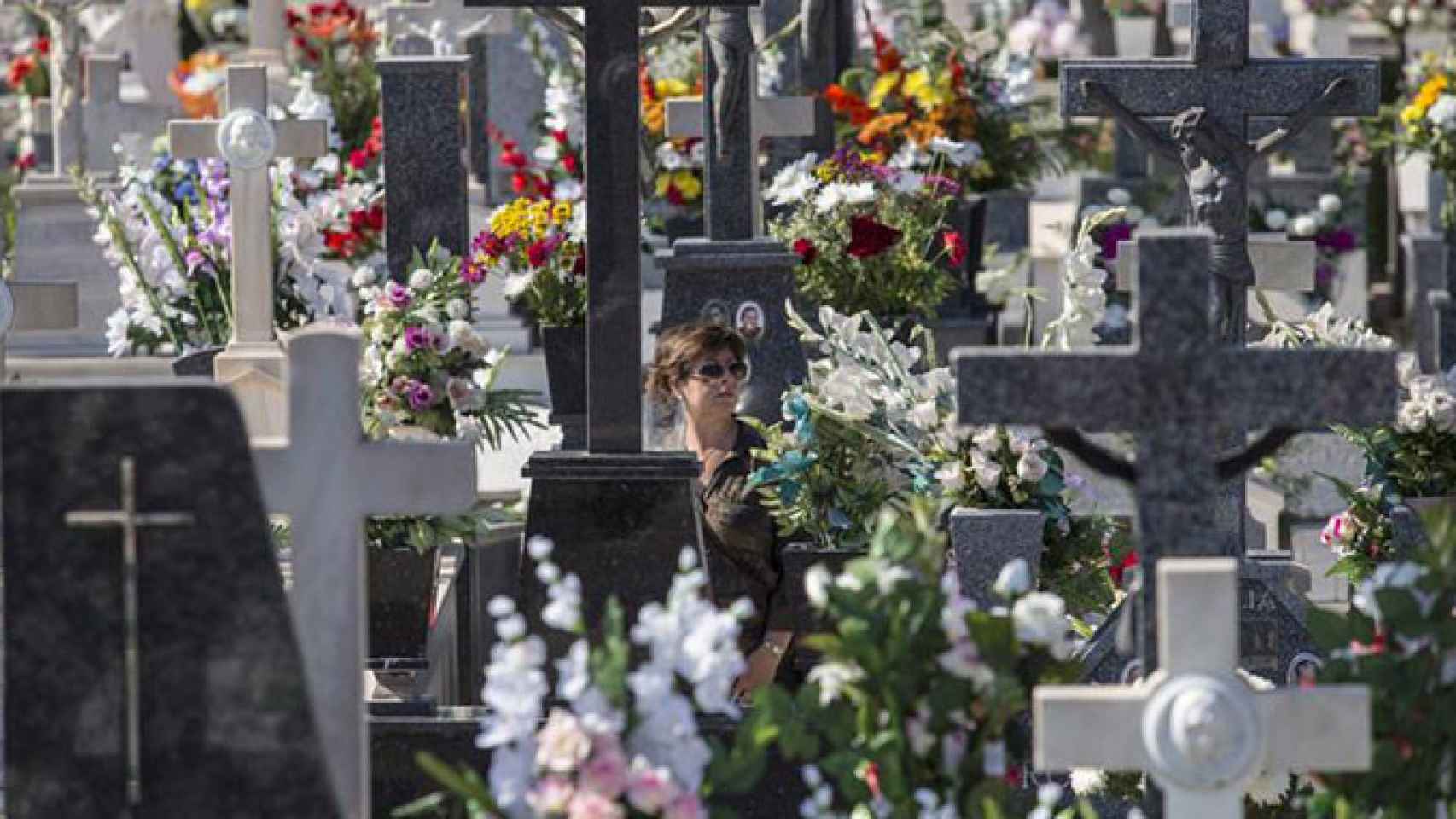 Una mujer en un cementerio lleno de flores / EFE