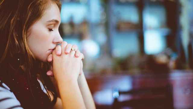 Una niña rezando en una iglesia / CG