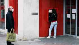 Dos ciudadanos ante un cajero automático del Banco Santander / EP