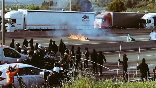 Un pequeño grupo de estudiantes con el rostro cubierto cortan una carretera en Cataluña