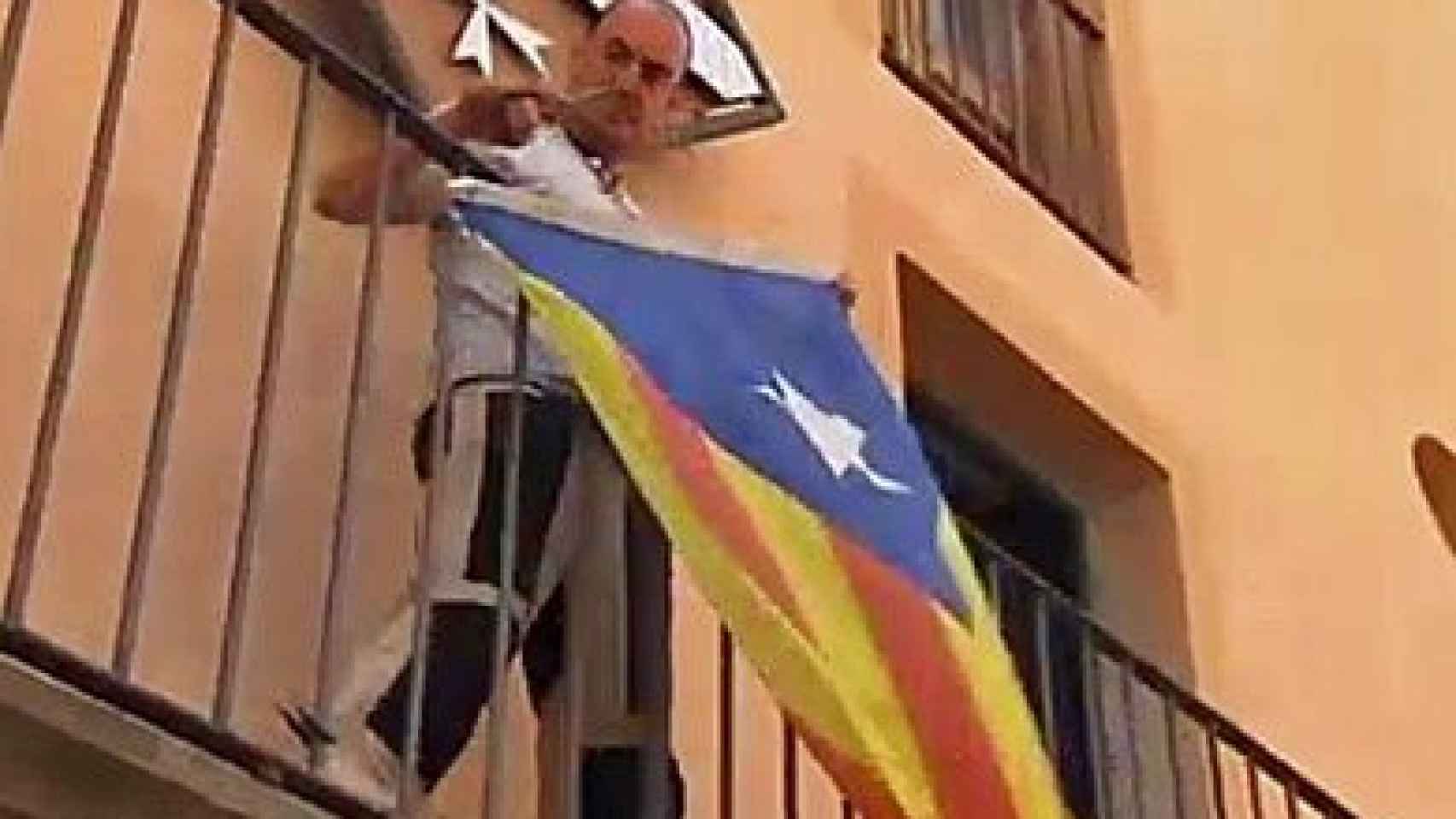El alcalde de Miravet (Tarragona), Antoni Joan Borrell, retirando la 'estelada' de la fachada del Ayuntamiento