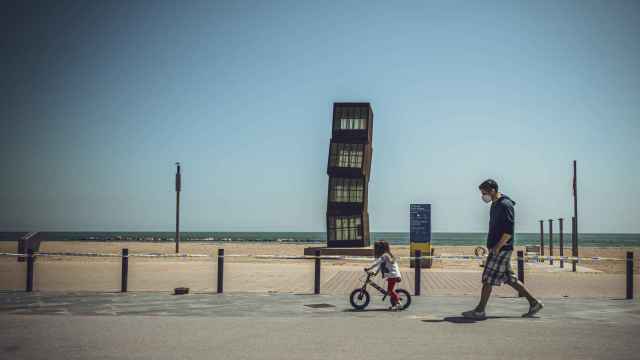 Un padre y su hija aprovechan las horas de sol para pasear por la playa de Barcelona / EP