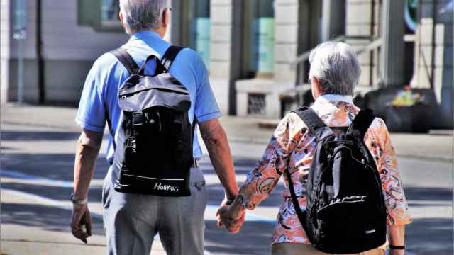 Dos personas mayores andan por la calle cogidos de la mano / CG