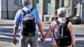 Dos personas mayores andan por la calle cogidos de la mano / CG