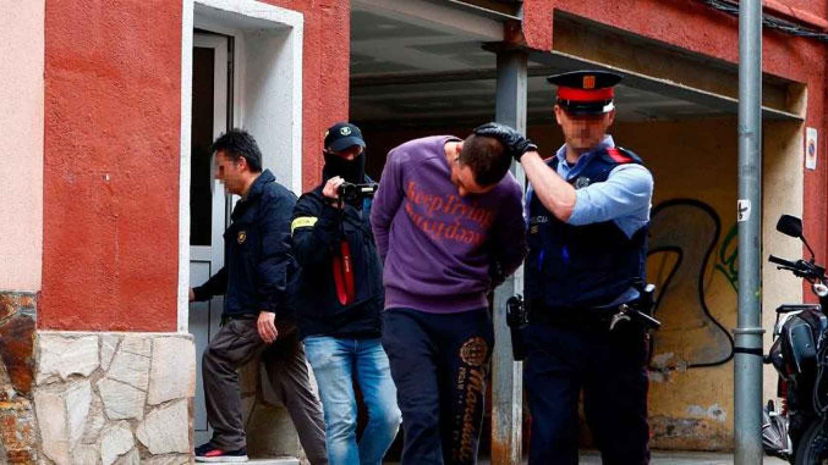 Un agente de los Mossos custodia a uno de los detenidos en Cornellà / EFE
