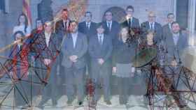 Foto de familia del Gobierno catalán encabezado por Carles Puigdemont y torres de telecomunicaciones.