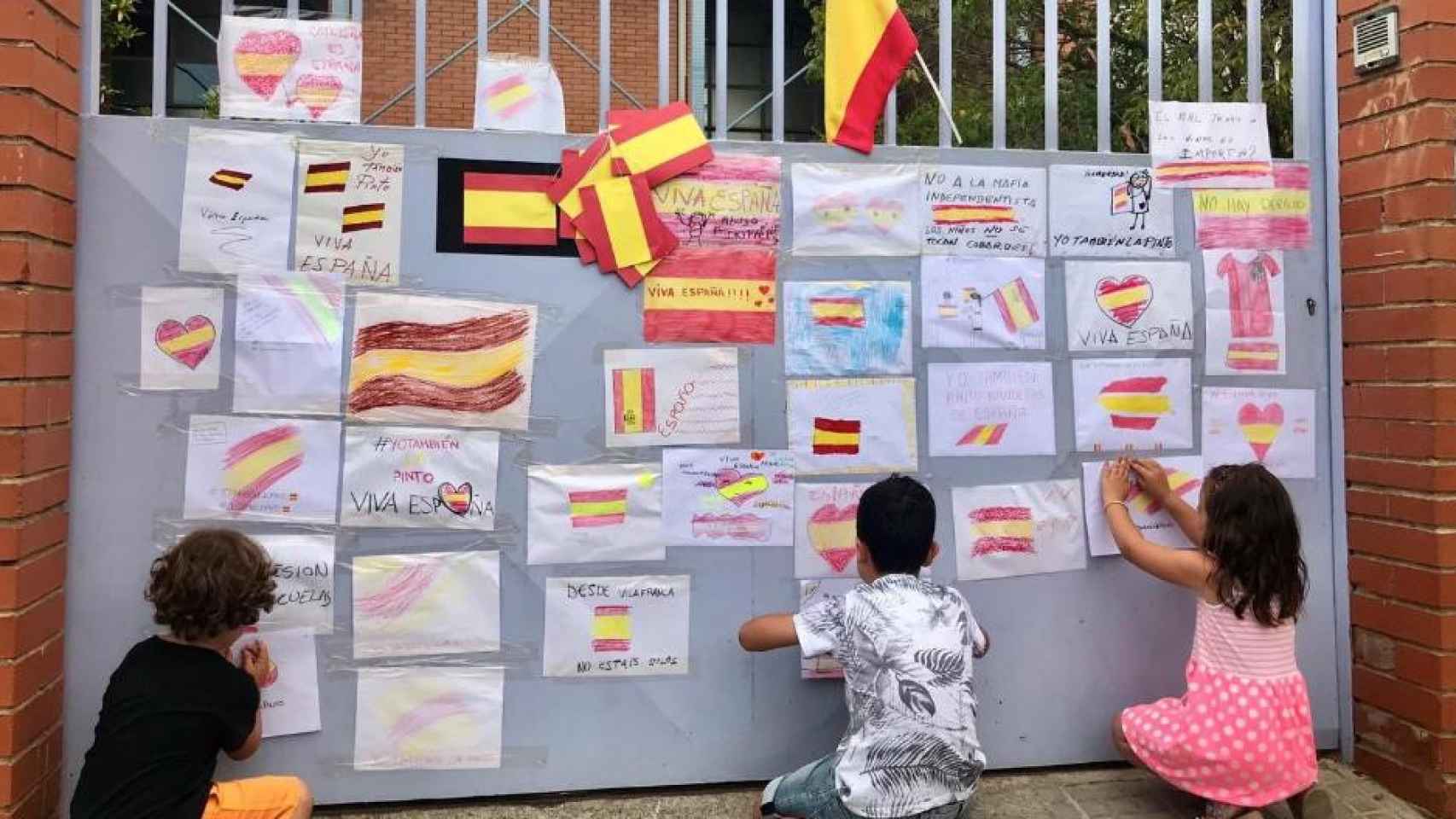 Unos niños cuelgan dibujos de banderas de España en la escuela Font de l'Alba de Terrassa / TWITTER