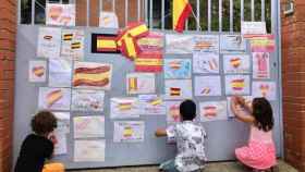 Unos niños cuelgan dibujos de banderas de España en la escuela Font de l'Alba de Terrassa / TWITTER