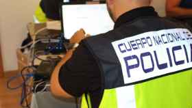 Un agente de la Policía Nacional inspecciona un ordenador como el del pederasta detenido en Barcelona / CNP