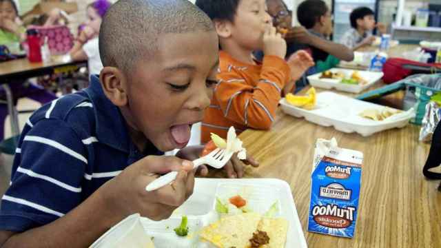 Niños comiendo comida basura en un comedor infantil / PIXNIO