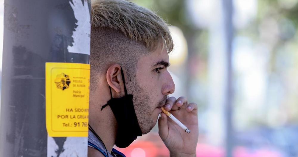 Un chico fuma con la mascarilla bajada durante la pandemia / EUROPA PRESS