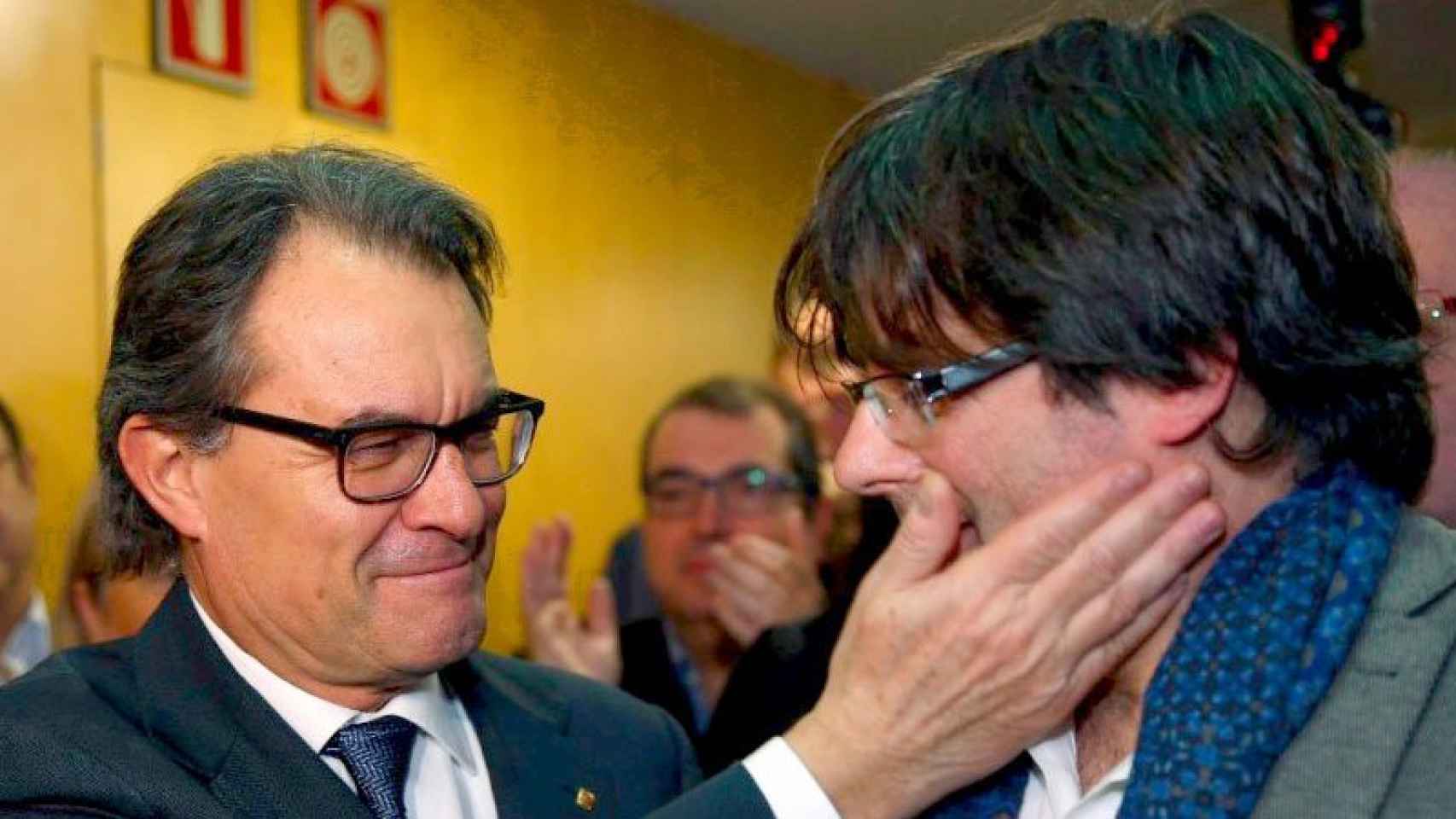El expresidente Artur Mas da un cachete cariñoso a su sucesor, Carles Puigdemont.