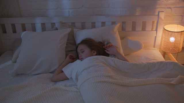 Una niña duerme con la luz de la lámpara encendida / PEXELS