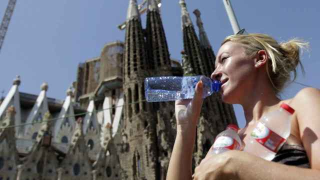 Una turista sacia la sed en las cercanías de la basílica de la Sagrada Familia de Barcelona / EFE