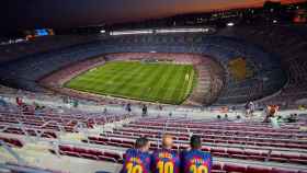 Una foto de tres aficionados del Barça en el Camp Nou / EFE