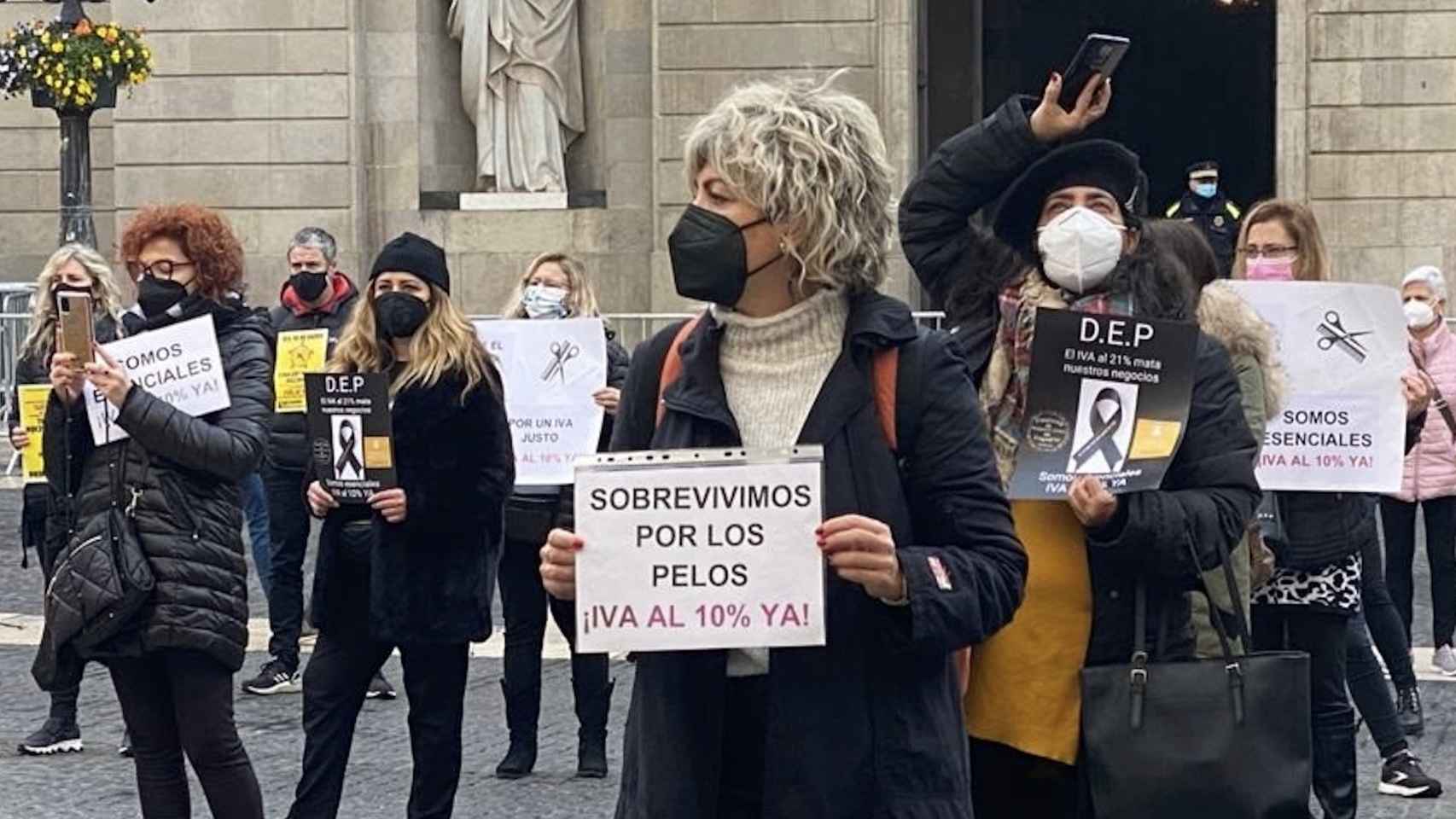 Una mujer sujeta un cartel durante la protesta de peluqueros en Barcelona  / EUROPAPRESS