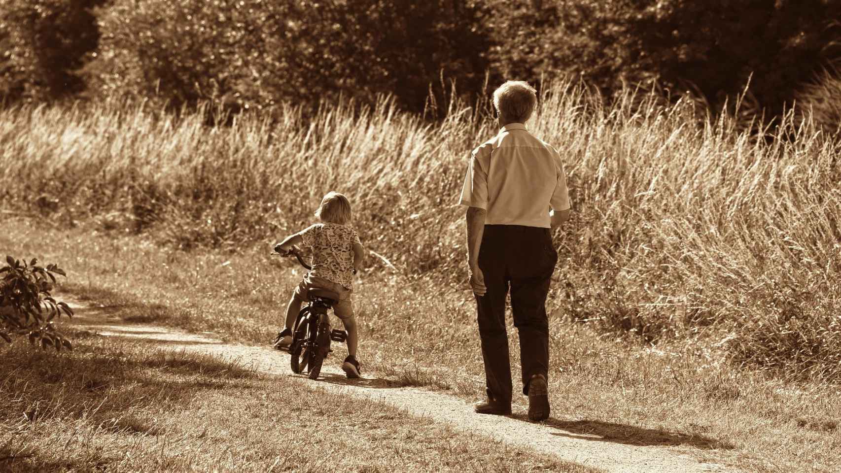Un abuelo acompaña a su nieta en su paseo en bicicleta / CG