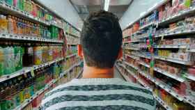 Un chico camina por un supermercado rodeado de comida y bebida / PIXABAY