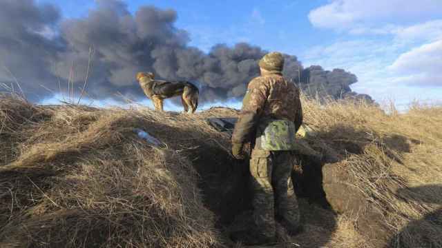 Un militar ucraniano y su perro observan el humo de un depósito de petróleo quemado tras el ataque de un misil ruso cerca de Kiev / EFE