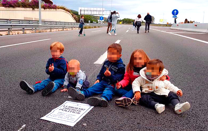 Bebés y niños sentados en la carretera con un cartel en el que se reclama la liberación de los presos políticos / CG