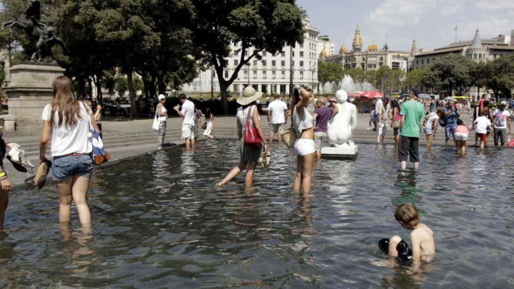 La gente se refresca en la fuente de Plaza Cataluña durante la ola de calor / EFE