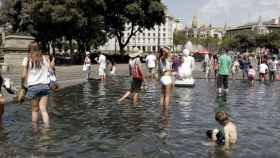 La gente se refresca en la fuente de Plaza Cataluña durante la ola de calor / EFE