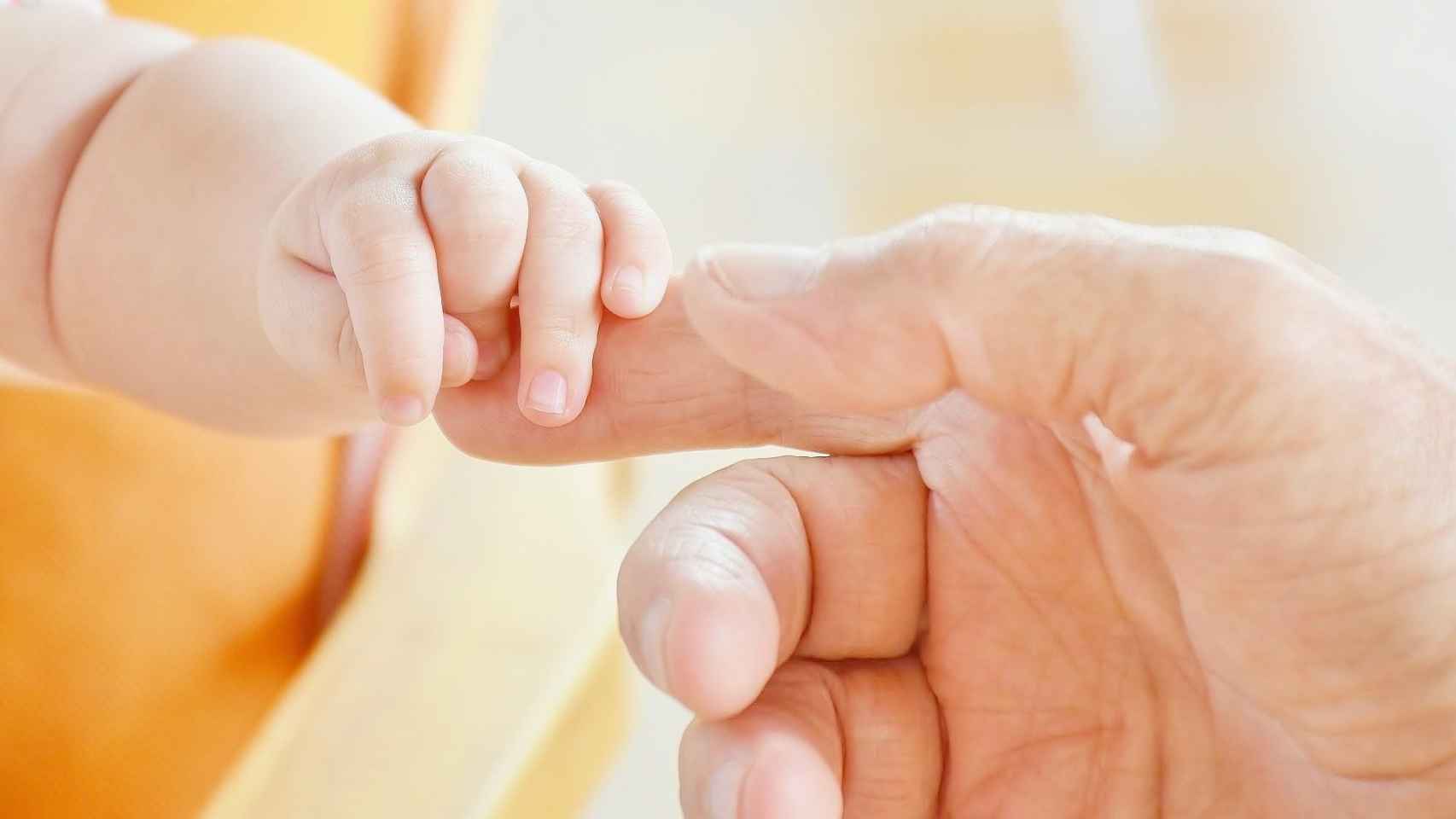 Imagen de archivo de un niño pequeño cogiendo de los dedos a un adulto / EUROPA PRESS