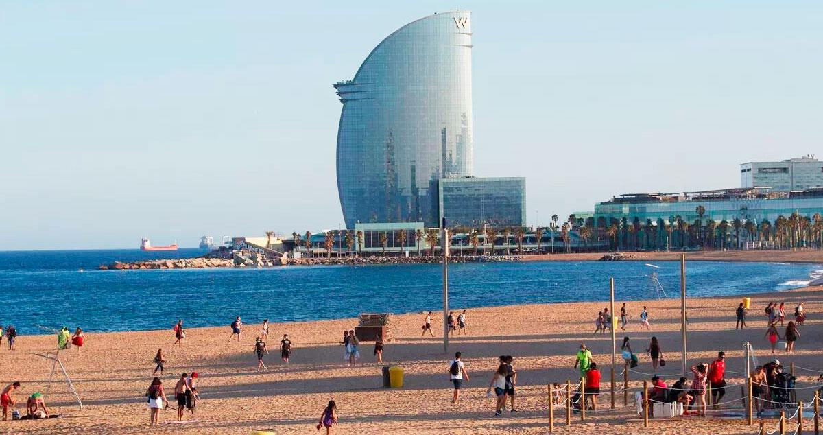 Imagen de una playa de Barcelona con el hotel W Barcelona en el horizonte / EFE