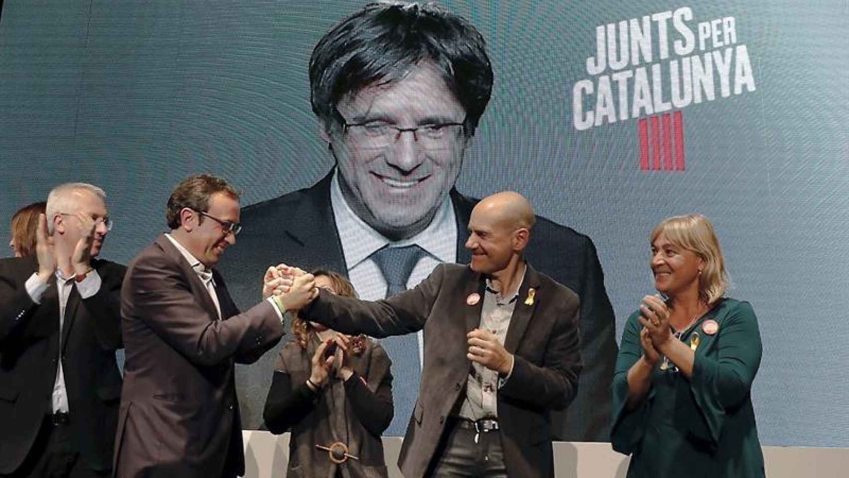 Carles Puigdemont, en la pantalla, en un acto de campaña de Junts pel Cataluña / EFE