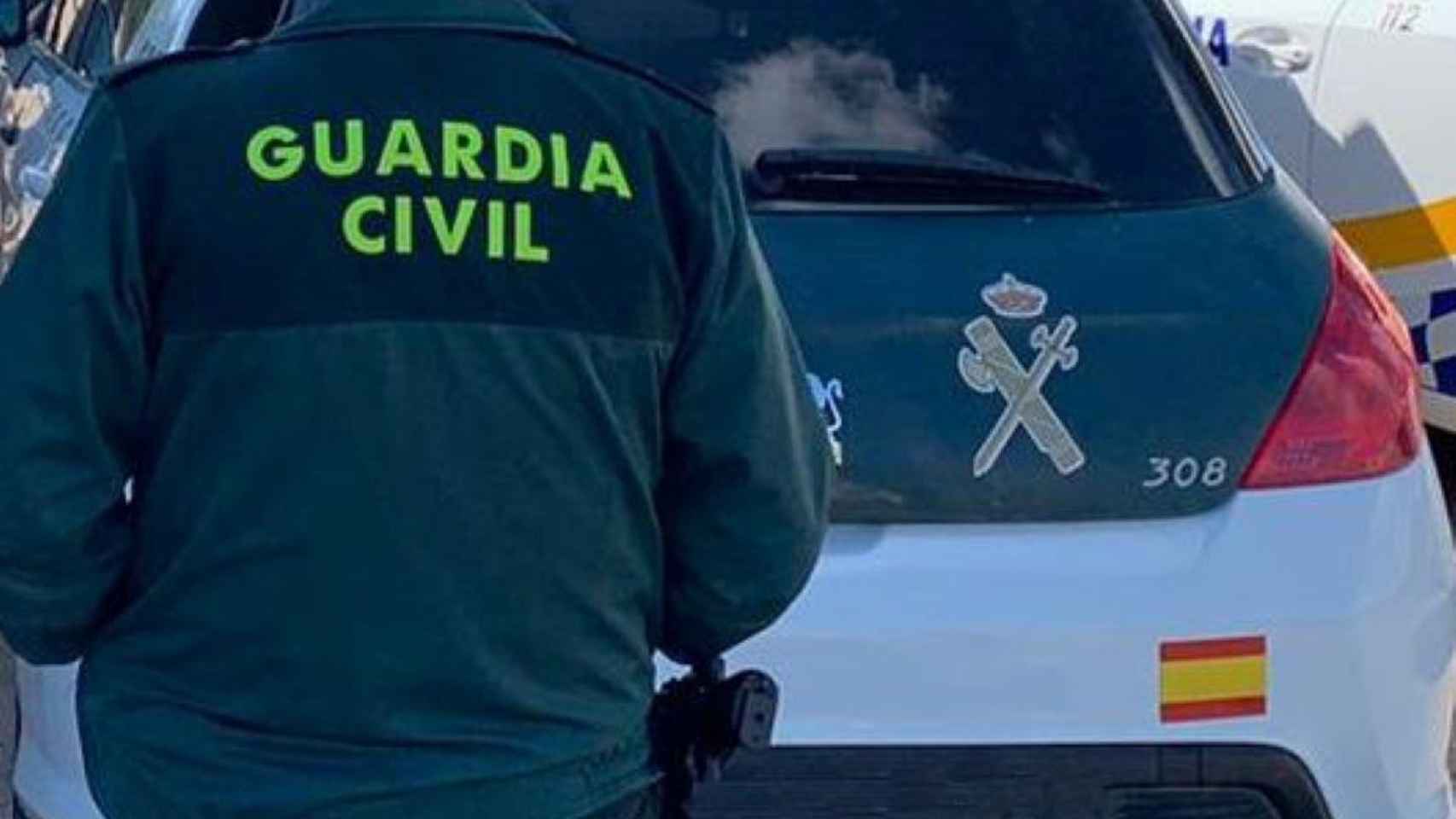 Un agente de la Guardia Civil de espaldas junto al vehículo oficial: encuentran una plantación en Llagostera / GUARDIA CIVIL