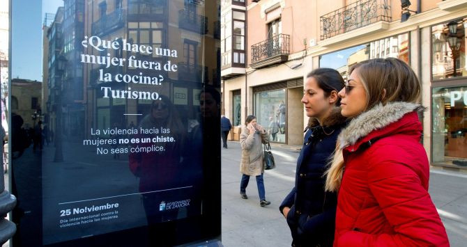 Dos chicas observan un cartel de la campaña contra la violencia machista en Zamora / EFE