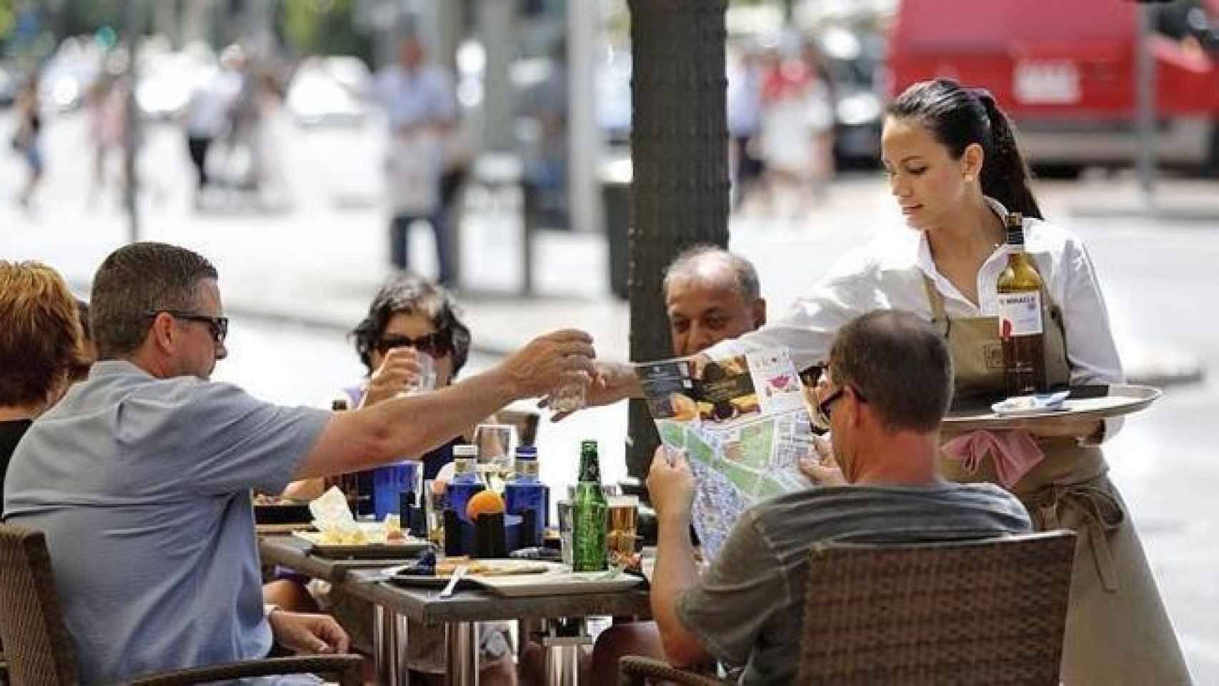 Una camarera atiende una mesa de turistas