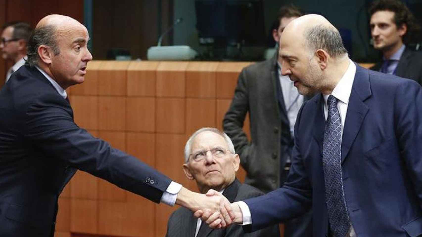 Luis de Guindos (i), ministro de Economía en funciones, estrecha la mano al comisario europeo de Economía, Pierre Moscovici (d), en presencia del ministro alemán Wolfgang Schaeuble.