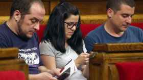 Los exdiputados de la CUP David Fernández, Isabel Vallet y Quim Arrufat, miran sus teléfonos móviles en el Parlamento catalán.