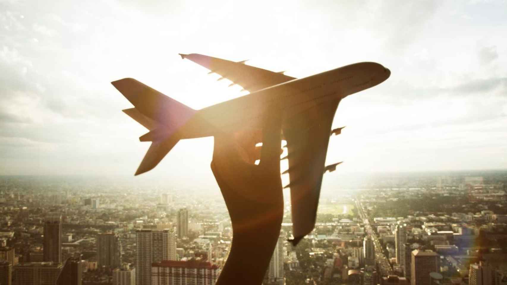 Una persona sujeta un pequeño avión mientras piensa en viajar / FREEPIK