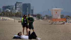 Dos informadores hablan con dos personas en la playa del Bogatell de Barcelona / EP