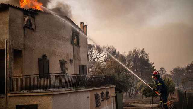 Un bombero apaga las llamas en una casa en Varibobi, al norte de Atenas / EUROPA PRESS