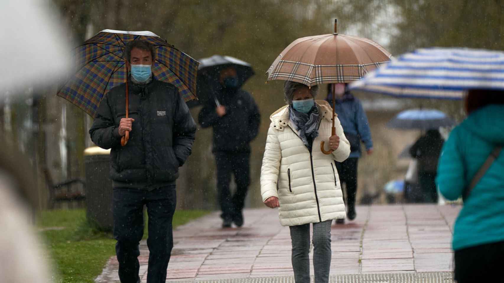 Imagen de archivo de varias personas refugiándose de las lluvias con un paraguas