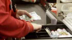 Una mujer manipula dinero de una caja registradora en un comercio / EFE