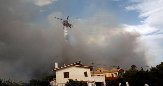 Un helicóptero sobre una vivienda incendiada en Penteli, al norte de Atenas / EFE