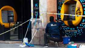 Un operario repara un cajero vandalizado y quemado durante los disturbios por Pablo Hasél / EFE