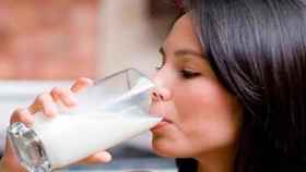 Una mujer bebe leche en un vaso