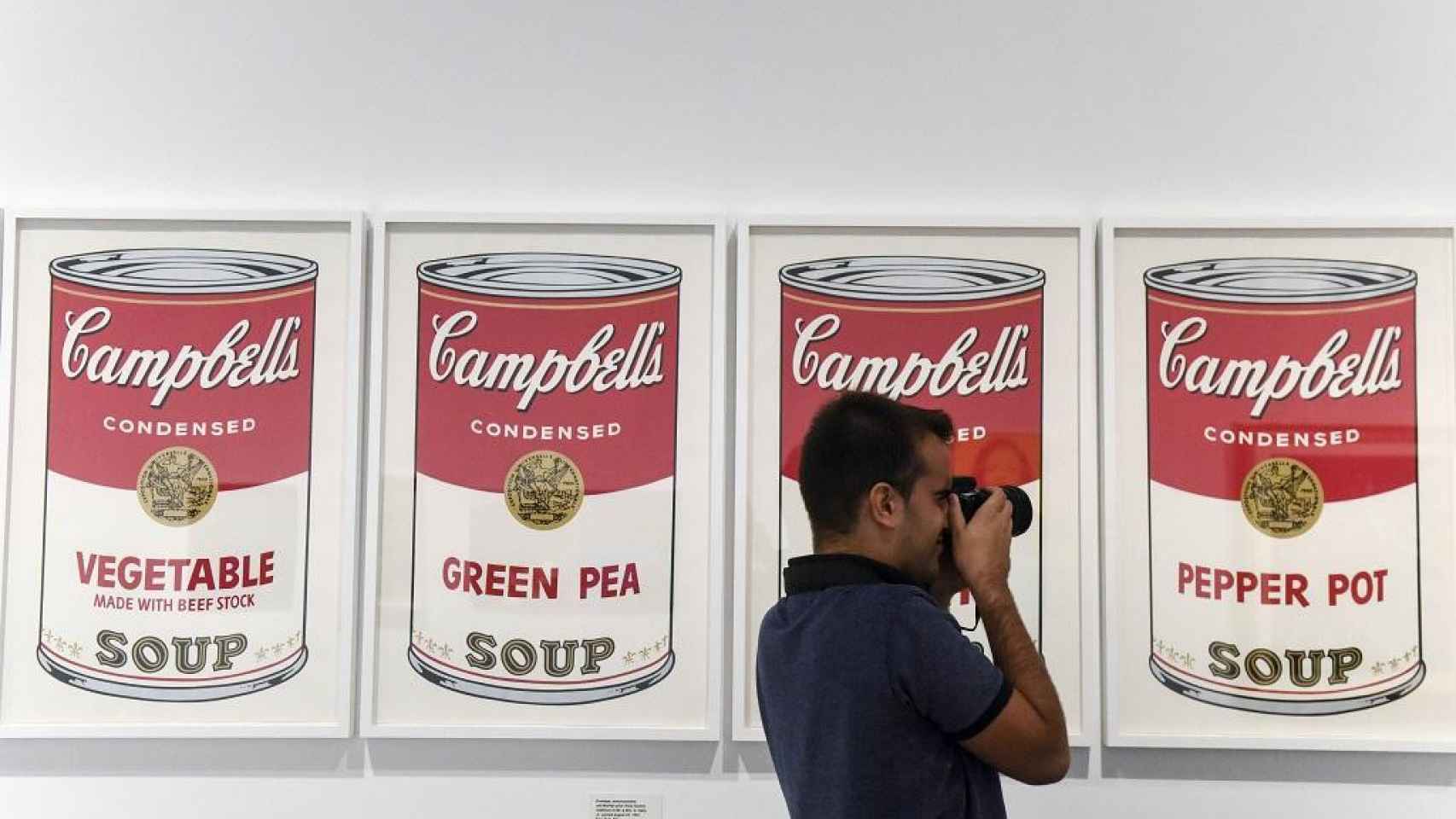 Un visitante toma imágenes de la sala de la serie de las sopas Campbell’s en ‘Warhol. El arte mecánico’. OBRA SOCIAL LA CAIXA