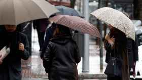 Transeúntes de Barcelona con un paraguas se protegen de la lluvia / EFE