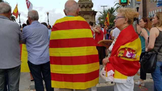 Una pareja envuelta en una señera catalana, él, y en una bandera española, ella, durante una Diada / CG