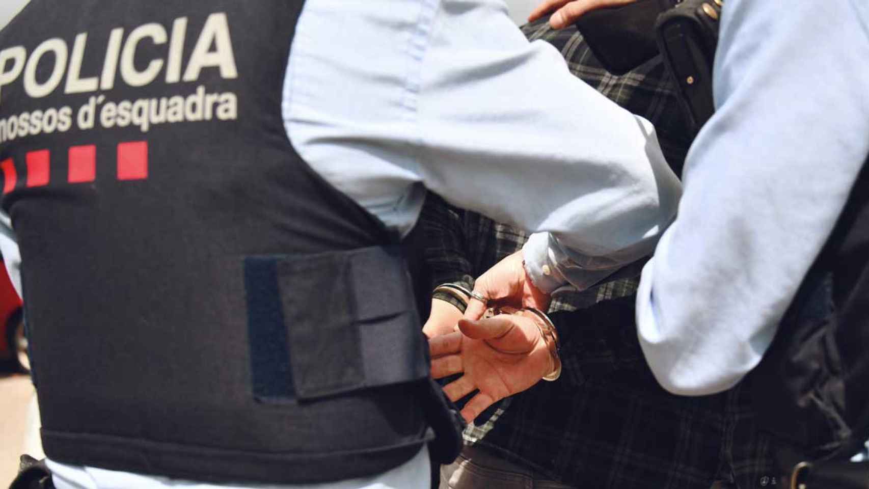 Dos agentes de los Mossos ponen las esposas a un detenido / MOSSOS