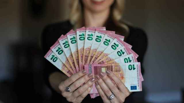 Una mujer muestra varios billetes de 10 euros